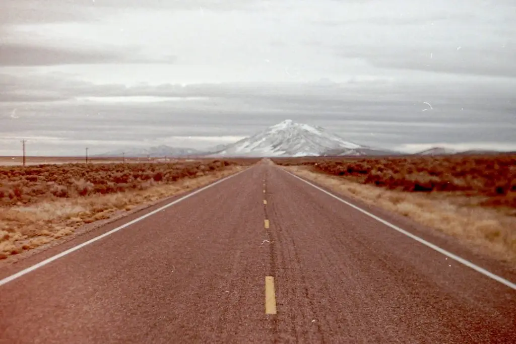 a long straight road with a mountain in the background