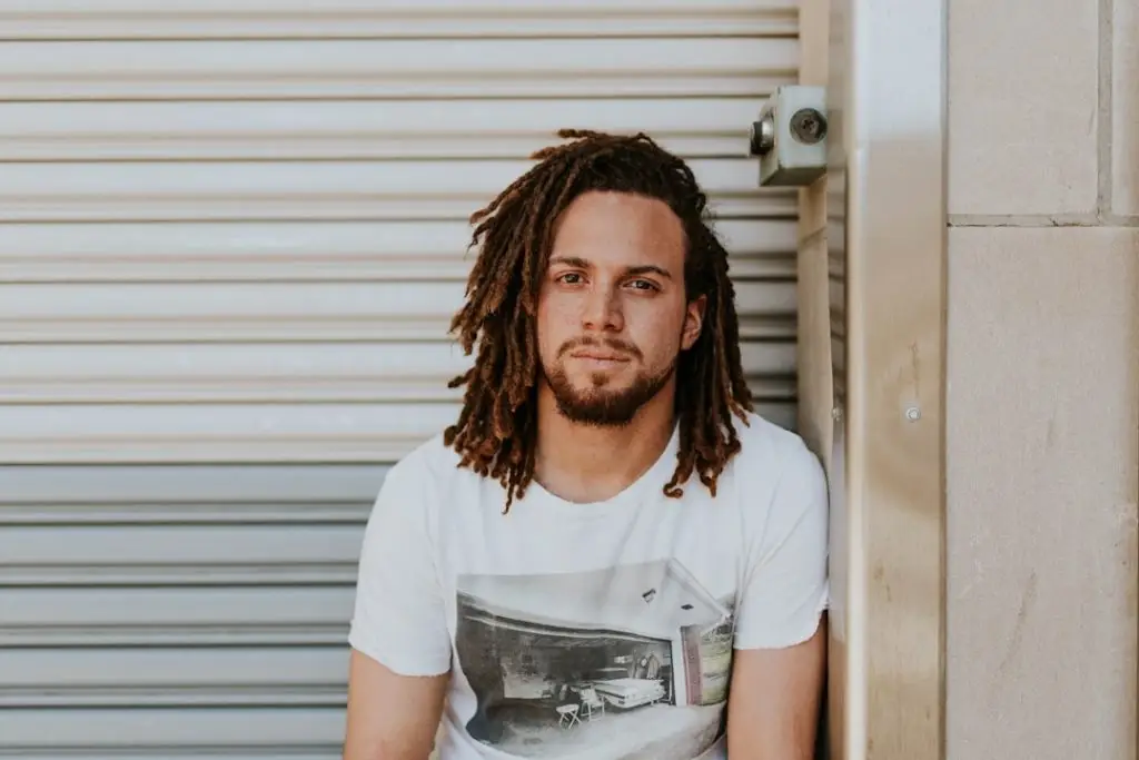 a man with dreadlocks leaning against a door