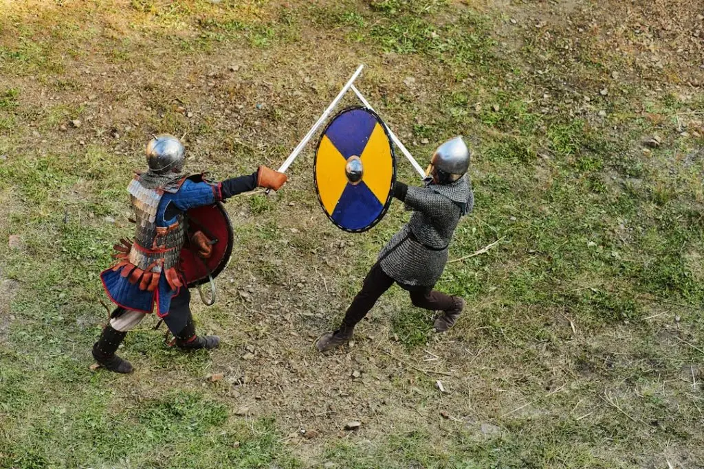 two men in armor holding shields and a sword