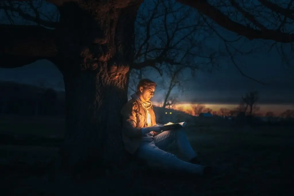 a man sitting under a tree reading a book