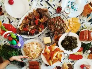 a table with plates of food and a person holding a glass