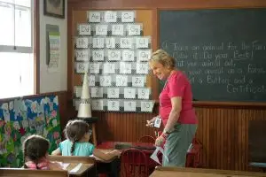 a woman standing in front of a classroom with a group of kids